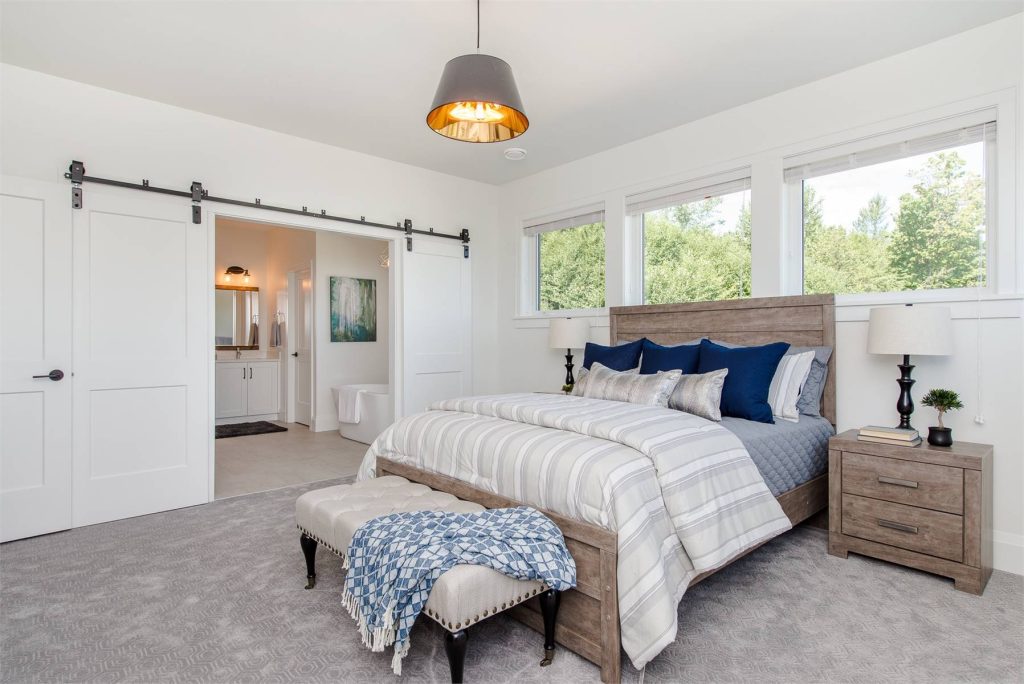 the great primary suite in a country home with a sunny bedroom and a private bathroom through barn doors